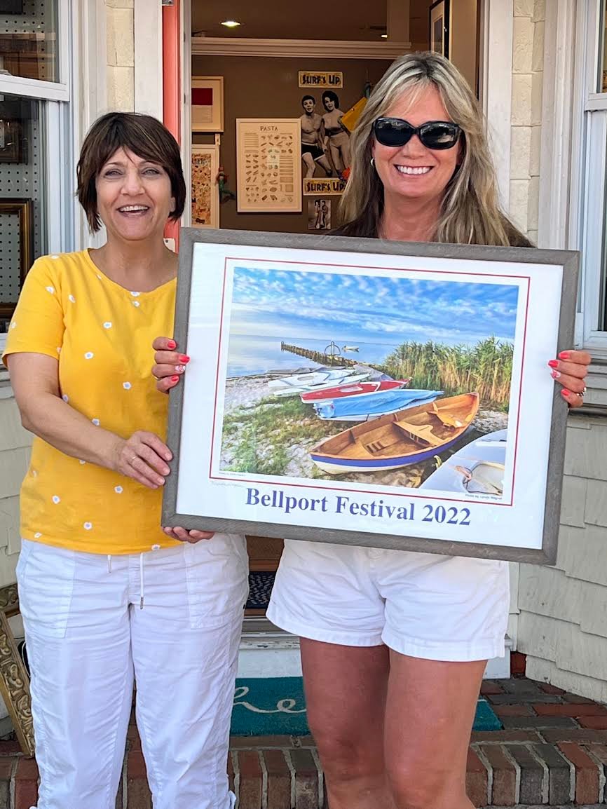 LuAnn Thompson, owner of Bellport Arts & Framing Studio, and Bellport Day Festival poster contest winner Lynda Wagner with her winning photograph of the Bellport Marina, which she spotted on a morning bike ride.